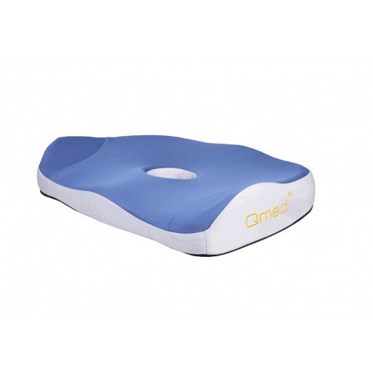 Възглавница Qmed Comfort с ергономичен дизайн и мемори пяна, поставена върху легло с неутрално спално бельо